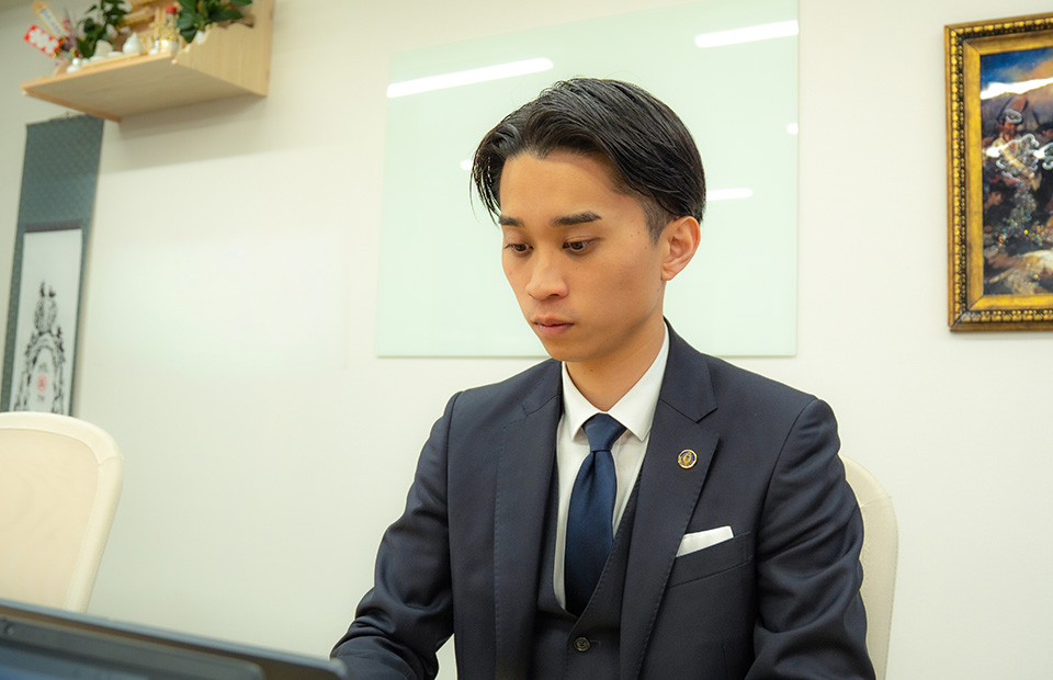 デスクでパソコンに向かい、集中して実務に取り組む若手男性スタッフ。