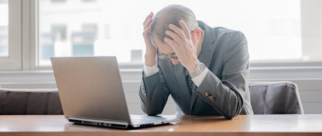 デスクで頭を抱える経営者のイメージカット
