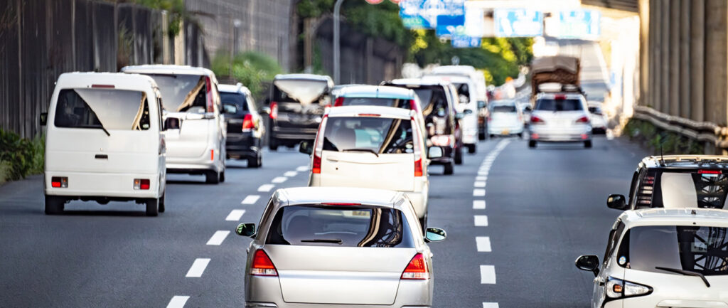日中の幹線道路で車列が続く交通風景